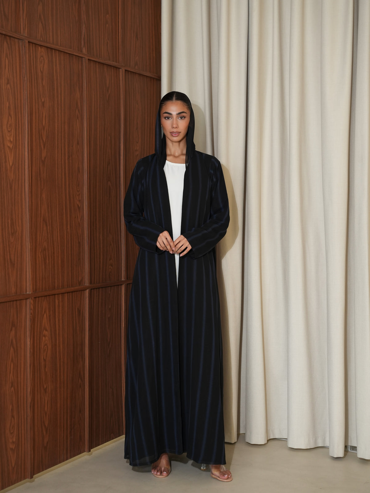 Model wearing a black hooded abaya with fine blue pinstripes